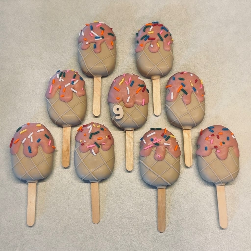 Pink-drizzled cakesicles topped with rainbow sprinkles